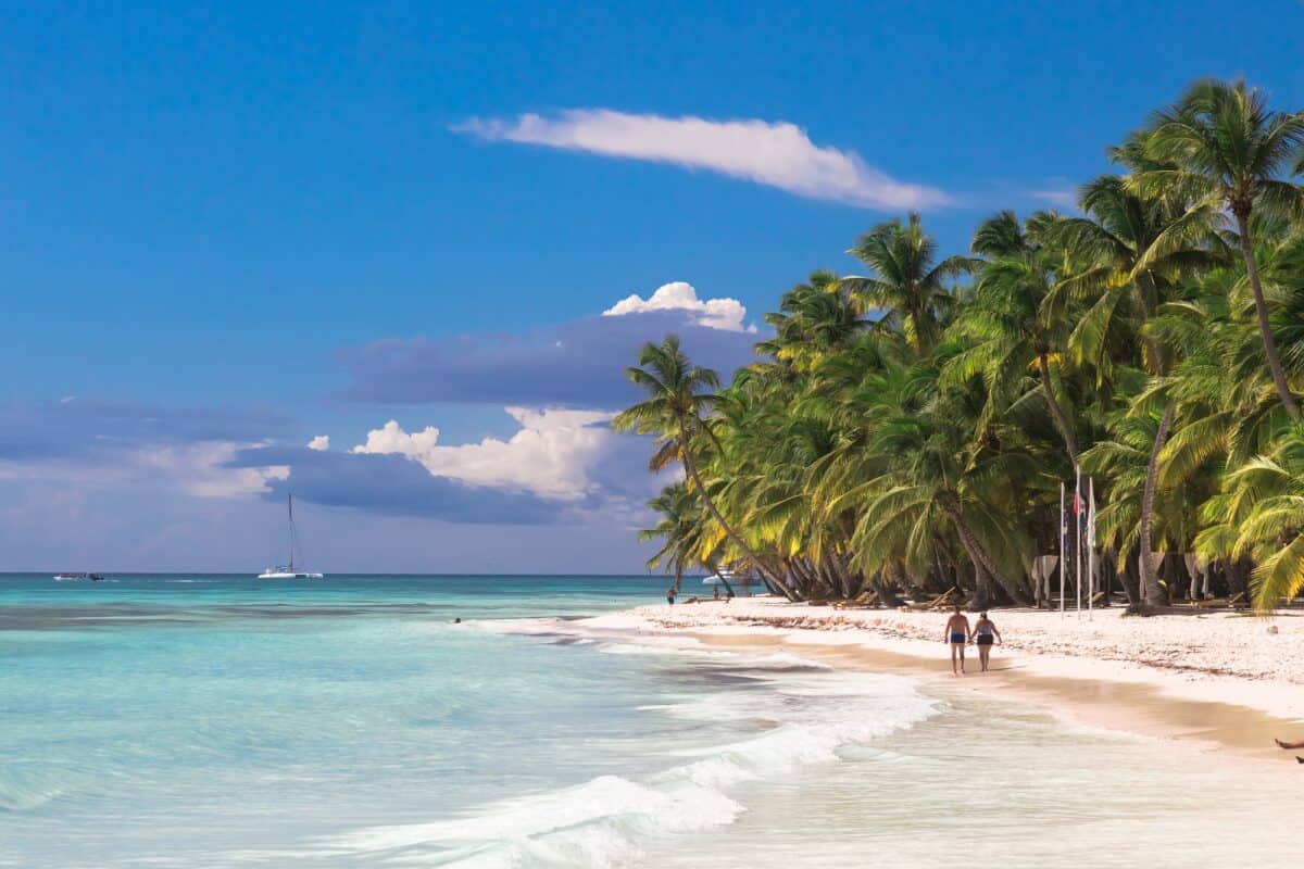 Couple walk on tropical island beach with perfect sunny sky