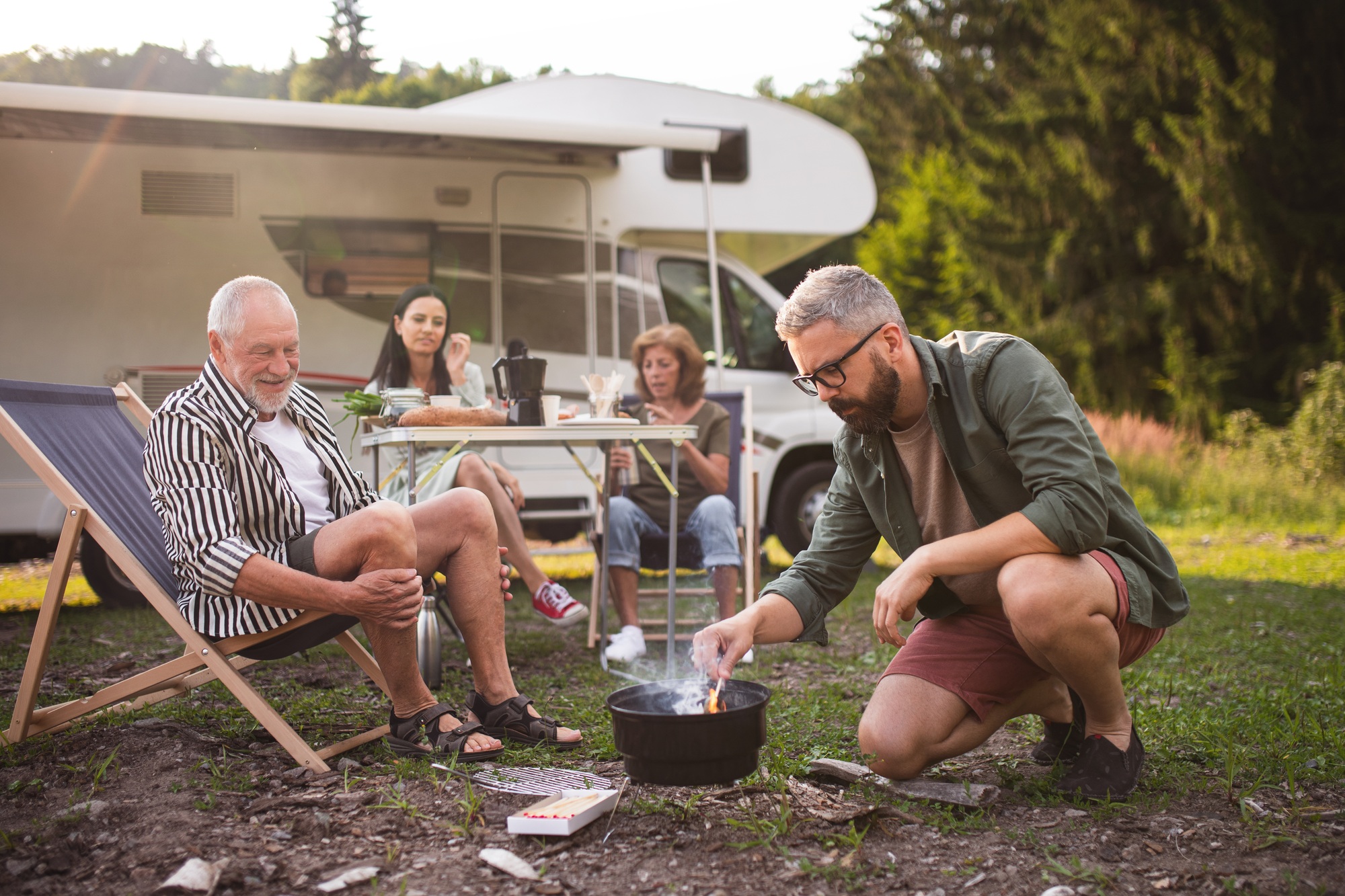 Famille multi-générationnelle préparant des repas sur le grill en voiture, en voyage de vacances en caravane