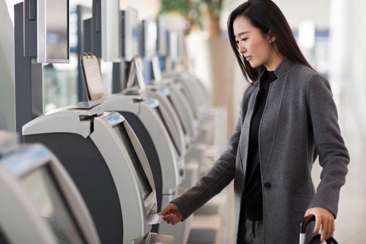 Businesswoman using ticket machine at the airport