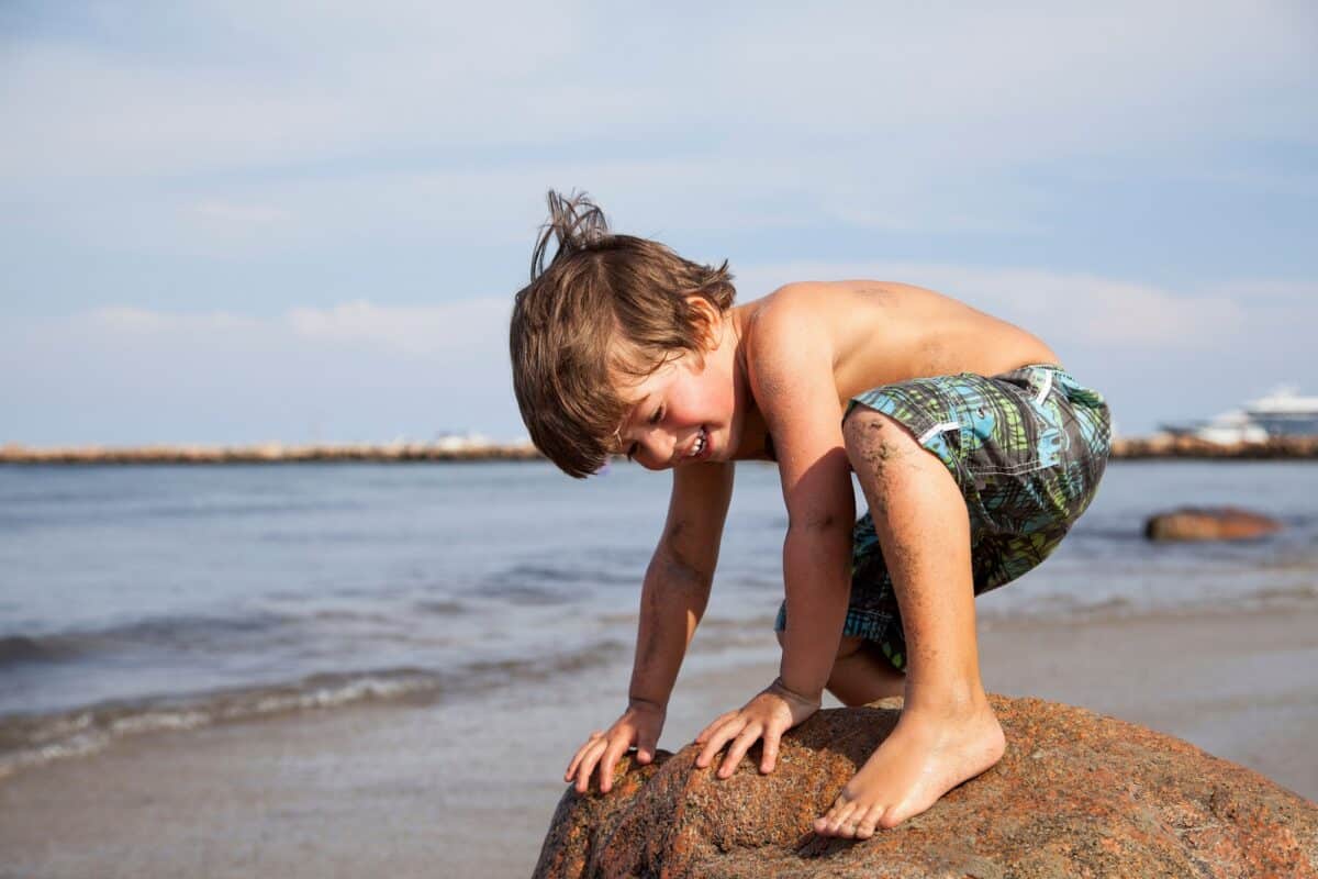 Boy crouching on rock on beach