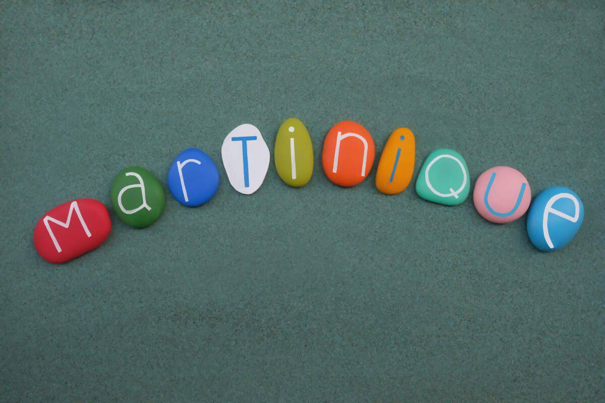 Martinique, France, souvenir composed with multi colored stone letters over green sand
