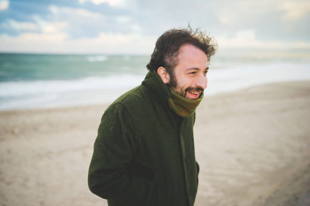Portrait of mid adult man on windy beach, Sorso, Sassari, Sardinia, Italy
