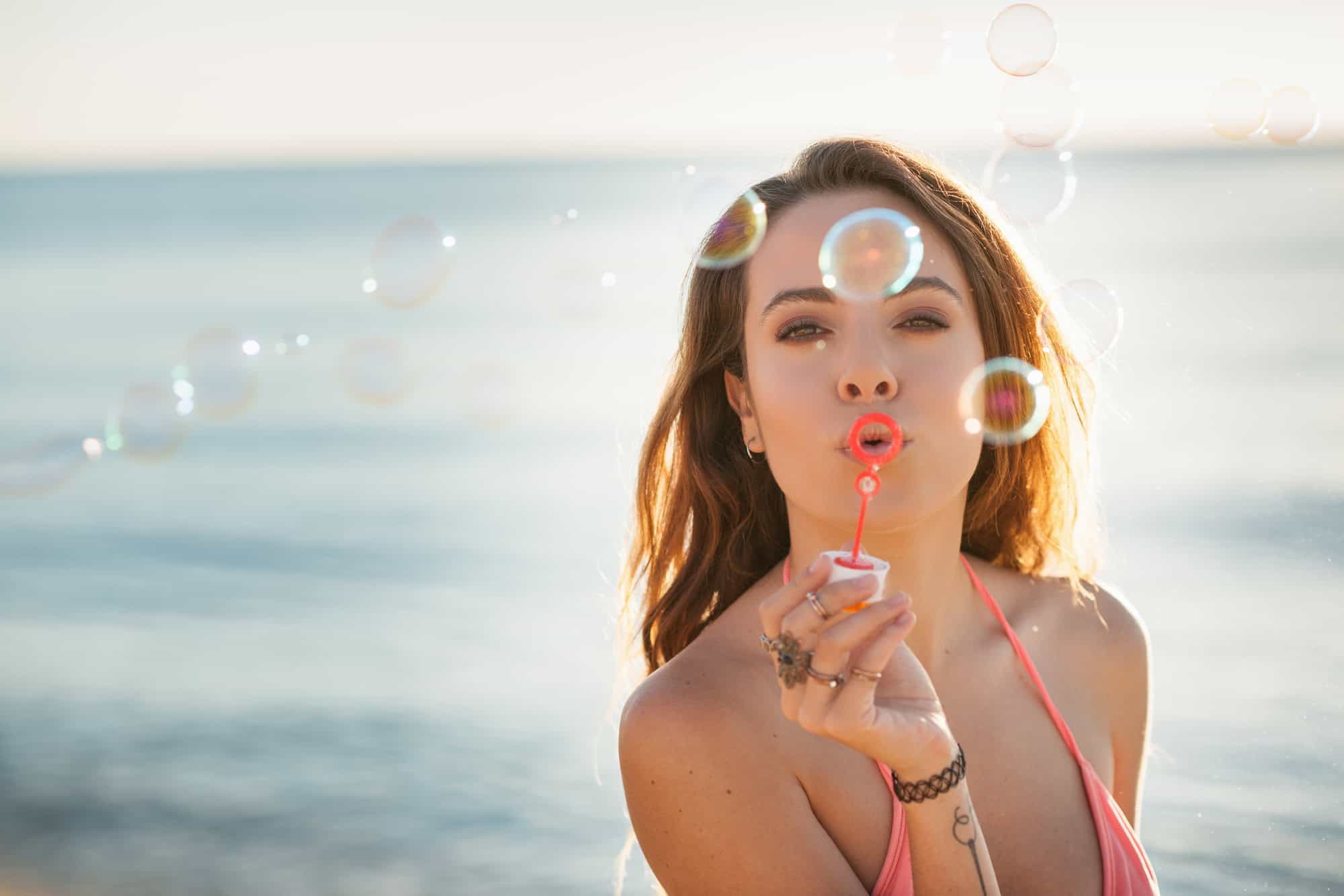 Portrait d'une jeune femme sur la plage soufflant des bulles, Castiadas, Sardaigne, Italie