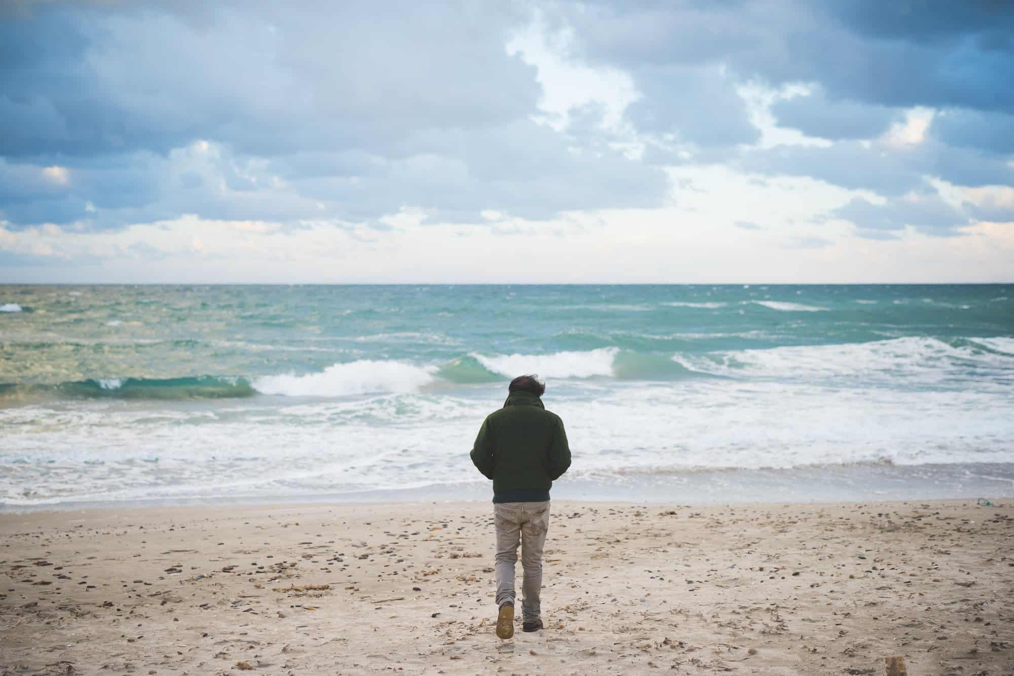 Vue arrière d'un homme sur une plage venteuse, Sorso, Sassari, Sardaigne, Italie